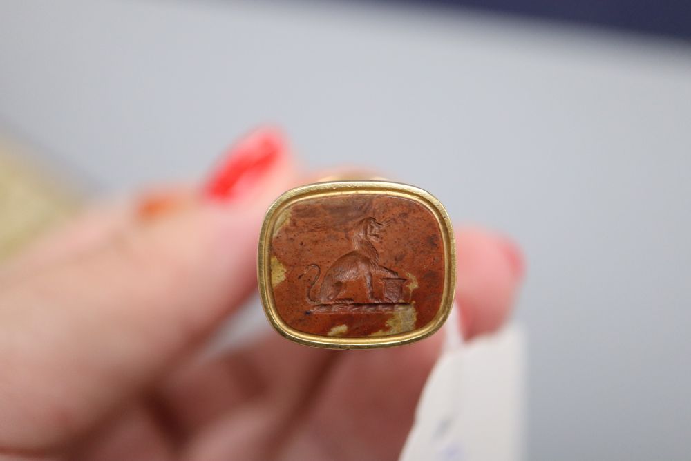 An early 20th century cased yellow metal mounted jasper seal with coral handle carved as a dragon (tail broken)